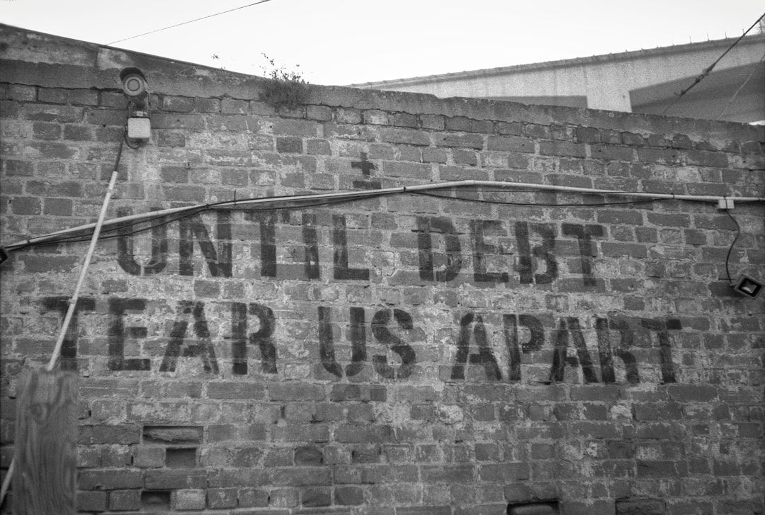 a sign on a brick wall that says until debt tears apart